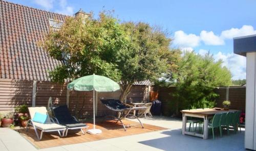 a patio with an umbrella and chairs and a table at White Sand Beach in Bergen aan Zee