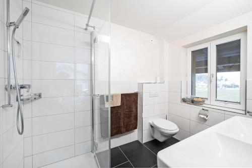 a white bathroom with a shower and a toilet at GLARNER Bed in Netstal