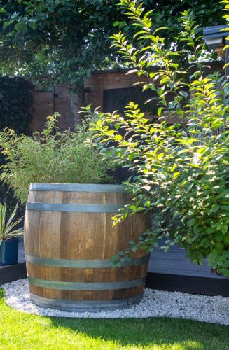 a large wooden barrel with plants in a garden at B&B Joli met privé wellness in Wemeldinge