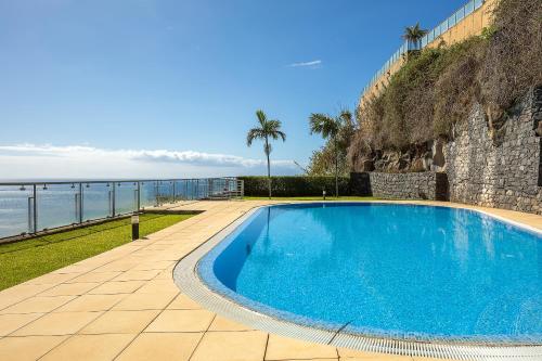 a large blue swimming pool next to the ocean at Apartamento Vale e Mar in Calheta