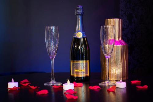 butelka wina obok dwóch kieliszków i świec w obiekcie Sweet SECRET'S JACUZZI w mieście Le Breuil