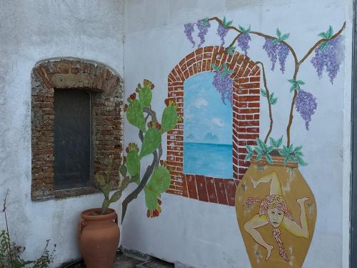 a wall with a painting of a window and a vase at Agriturismo Serre in SantʼAgata di Militello