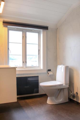 a bathroom with a white toilet and a window at Hotel Lyngørporten in Gjeving