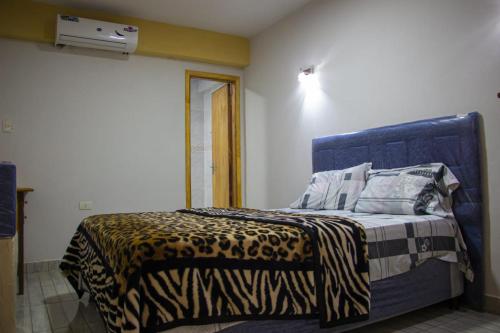 a bed with a blue headboard in a room at Ullanka Apart Hotel in Encarnación