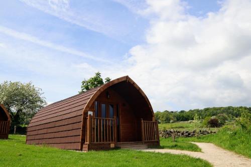 a small wooden barn in a field with a dirt road at Saints' Meadow in Crich