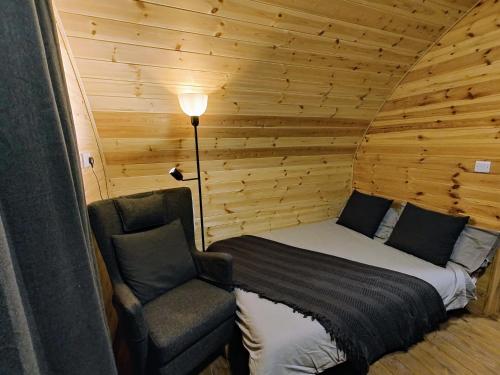 a bed and a chair in a log cabin at Saints' Meadow in Crich