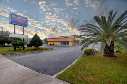 a sign for a hotel on a street with a palm tree at Budget Inn West Melbourne in Melbourne