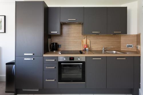 una cucina con armadi neri, lavandino e piano cottura di London Mews, modern apartment - sleeps 4 a York