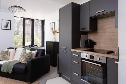 a kitchen with black cabinets and a living room at London Mews, modern apartment - sleeps 4 in York