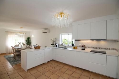 a kitchen with white cabinets and a dining room at Villa Ílios - Porto de Mós, Lagos in Lagos