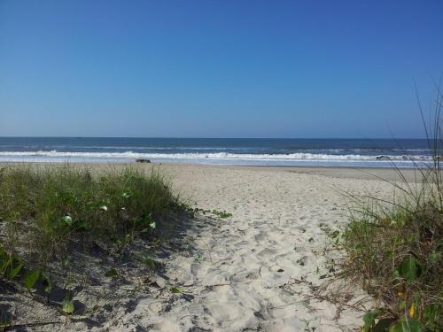 a sandy beach with some grass and the ocean at Kaakupe Praia Hotel in Guaratuba