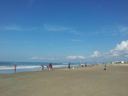 a group of people standing on a beach at Kaakupe Praia Hotel in Guaratuba