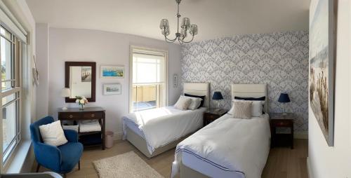 a bedroom with two beds and a blue chair at Radharc Na Cuilcagh in Enniskillen