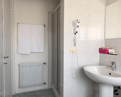 La salle de bains blanche est pourvue d'un lavabo et d'une douche. dans l'établissement Hotel all'Oasi, à Paese