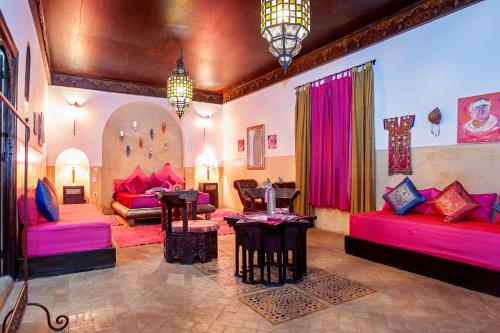 a living room with pink couches and tables at Riad Dar Nadwa in Marrakesh