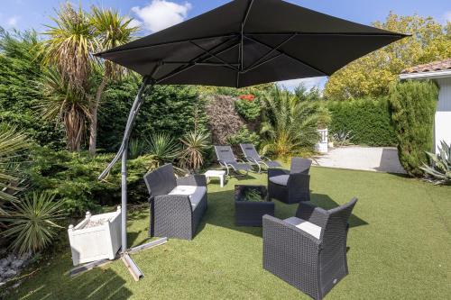 a group of chairs and an umbrella on a lawn at Maison De Vacances 8pers Seignosse in Seignosse