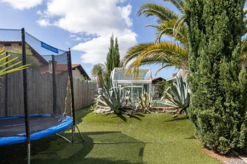a backyard with a trampoline and palm trees and a fence at Maison De Vacances 8pers Seignosse in Seignosse