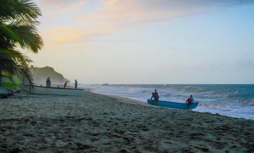 a group of people standing on a beach with boats at Glamping - Habla con la Luna in Santa Marta