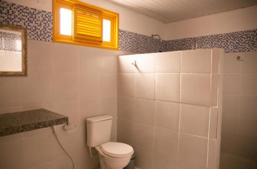 uma casa de banho com um WC branco e uma janela em Pousada dunas em Luís Correia