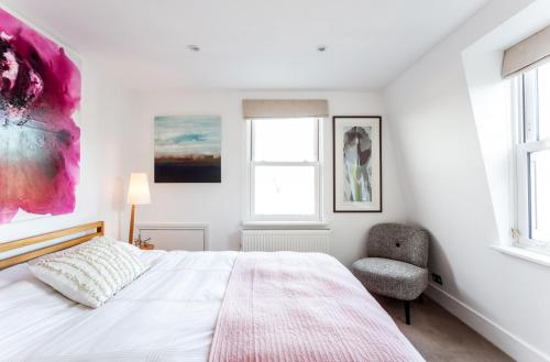 a white bedroom with a bed and a chair at Elephant & Oxpecker in Fulham in London