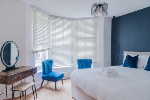 a bedroom with a bed and two blue chairs and a mirror at Blue Notes in Westbourne Park in London