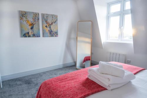 a bedroom with a bed with a red blanket and a mirror at Newly Refurbished 2 bed with Fantastic View in London