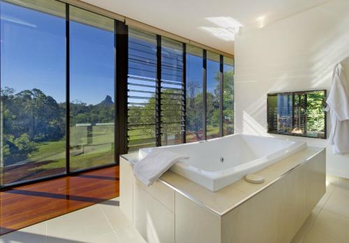 a white bathroom with a tub and large windows at Glass On Glasshouse in Glass House Mountains