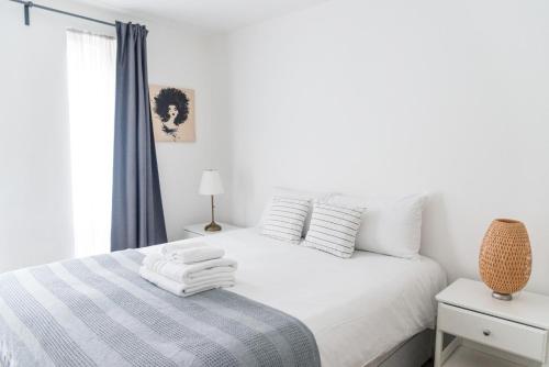 Un dormitorio blanco con una cama con toallas. en The City Song in Rotherite en Londres