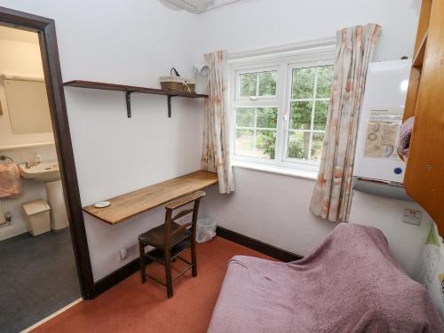 ボートン・オン・ザ・ウォーターにあるNewbury Cottageのデスクと窓が備わる小さな客室です。