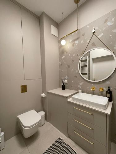 uma casa de banho com um WC, um lavatório e um espelho. em APARTAMENT OVOC GDYNIA NOWE KOLIBKI em Gdynia