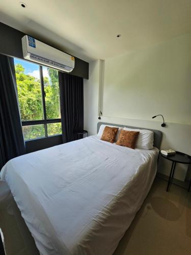 a bedroom with a large white bed with a window at Aya Residence Garden View in Ban Ket Ho