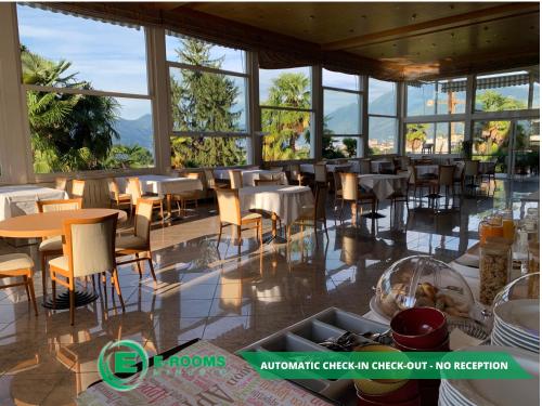 un restaurant avec des tables, des chaises et des fenêtres dans l'établissement E-Rooms Minusio, à Locarno