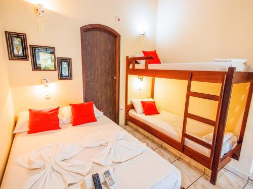 2 literas en una habitación con almohadas rojas en VELINN Pousada Mirante da Praia Grande, en Ilhabela