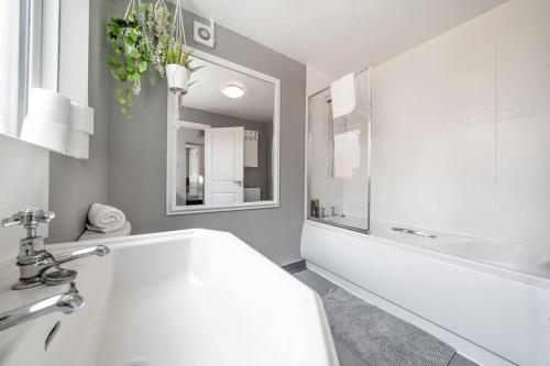 La salle de bains blanche est pourvue d'un lavabo, d'une baignoire et d'un miroir. dans l'établissement Cosy 2 Bedroom Town House Close To City Centre, à Belfast