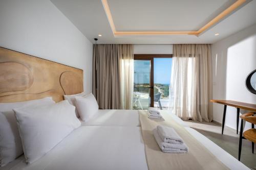 1 dormitorio con 1 cama blanca grande y balcón en Mika Villas & Suites, en Hersonissos