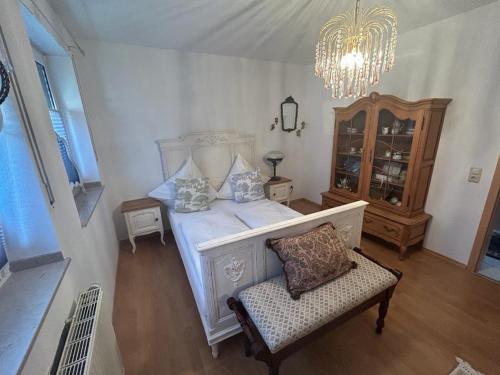 a bedroom with a white bed with a chair and a chandelier at Vintage Traum in Hückelhoven