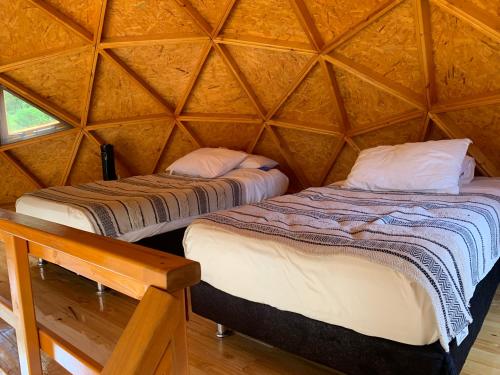 two beds in a yurt with a wooden wall at Las Nubes Domo in La Mesa