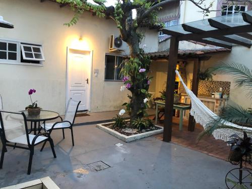 d'une terrasse avec une table, des chaises et un arbre. dans l'établissement Loft para temporada, à Cabo Frio