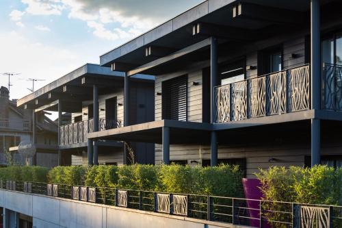 an apartment building with balconies and plants on the side at Le Kube - Appartements de Prestige au centre d'Annecy in Annecy