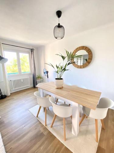 une table à manger avec des chaises blanches et une plante en pot dans l'établissement l'emplacement idéal-Free parking à 5mn du centre, à Wintzenheim