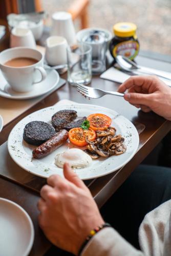 a person sitting at a table with a plate of food at Eriskay B&B and Aviemore Glamping in Aviemore