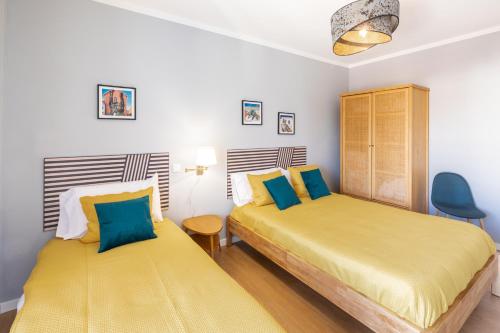 - une chambre avec 2 lits dotés d'oreillers jaunes et bleus dans l'établissement Modern 3 bedrooms 3 bath apartment 5 minutes walk from the Santuary, à Fátima