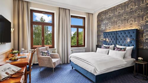 ein Hotelzimmer mit einem Bett, einem Schreibtisch und Stühlen in der Unterkunft Hotel Bayerischer Hof Dresden in Dresden