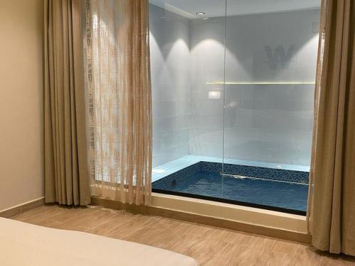una piscina vista a través de una ventana de cristal en un dormitorio en شاليهات دبليو سويتس الدرب en Qarār