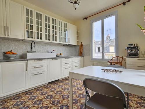 une cuisine avec des placards blancs et une grande fenêtre dans l'établissement Maison familiale, 3 chambres, jardin, au calme, à Trouville-sur-Mer