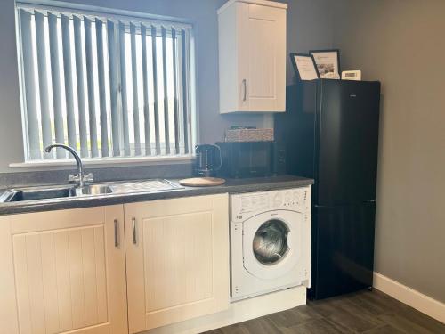 a kitchen with a washing machine and a black refrigerator at The Gainsborough Mews-stylish & modern (sleeps 3) in Lincolnshire