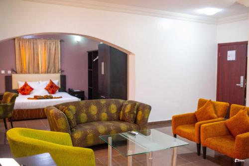a hotel room with a bed and a couch and chairs at Suru Express Hotel GRA in Ikeja