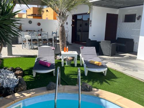 einen Hinterhof mit einem Pool, Stühlen und einem Tisch in der Unterkunft Villa Papi in La Oliva