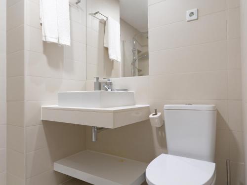 a white bathroom with a toilet and a sink at Madeira apartment in Mindelo São Vicente in Mindelo
