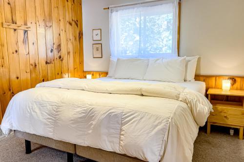 a bedroom with a bed with white sheets and a window at Lucy Lake Lookout in Lac du Flambeau
